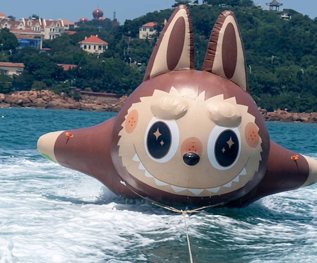 Brown inflatable character tube skimming across the water while being towed