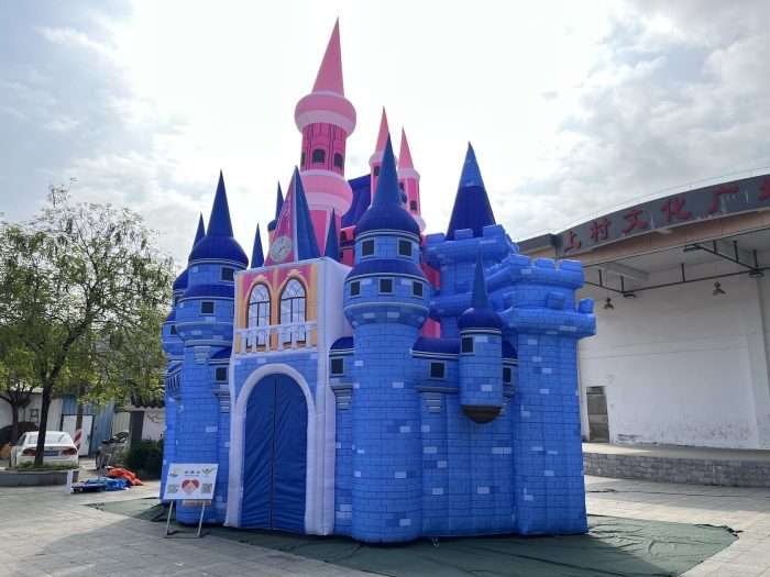 Inflatable fairytale castle tunnel displayed outdoors at event with multiple towers