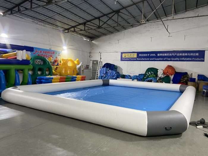 Large rectangular inflatable pool with gray walls and blue base in warehouse, 10x8m
