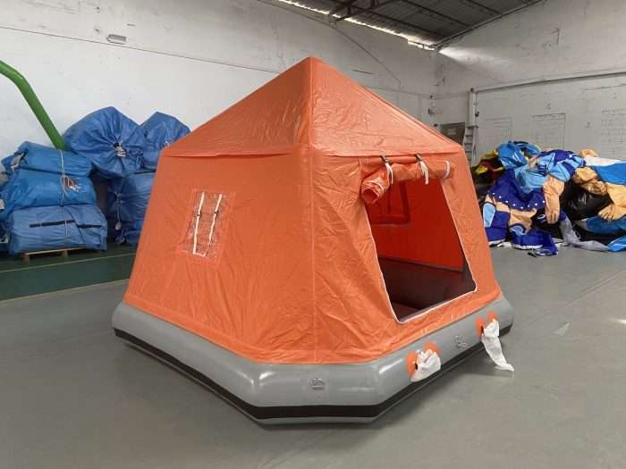 Orange inflatable rafting tent with mesh window and rolled-up door flap, warehouse view