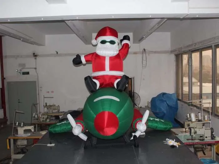 Front view of sunglasses-wearing inflatable Santa Claus sitting on toy airplane, 3m, 9kg